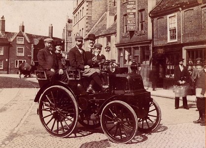 The Grapes - c1900. Image provided by Don Ferguson, New York State.   ``Would you know someone who can fill me in as to the make and year of the automobile pictured there and, perhaps, the names of the shops nearby?  I have to assume that the picture contains one or more of my relatives.  My grandfather, Horace Ward, had a shop somewhere in King's Lynn.  He sold or made (or both) bicycles, among other things.  He married the former Emily Forman, had three children (Sidney, Alice - my mother, and a boy who died in childhood) and moved to Welland, Ont., Canada sometime before 1920. Any help you can give is appreciated.''
